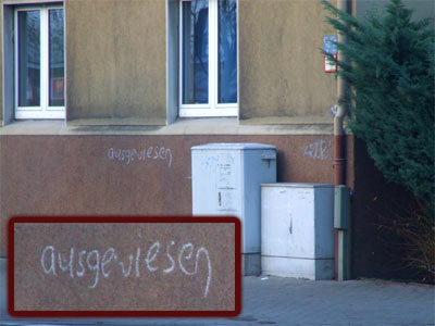 an einer Hauswand steht mit Kreide das Wort "ausgewiesen"